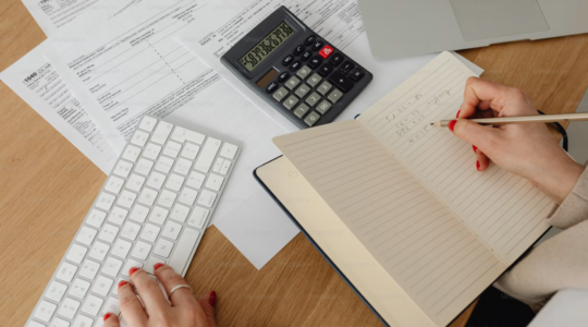 bureau où est posé un cachier, une calculatrice et des documents